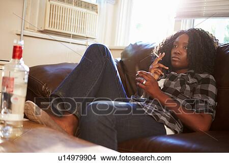 Woman Sitting On Sofa With Bottle Of Vodka And Cigarettes View Large Photo Image Picture - Woman Sitting On Sofa With Bottle Of Vodka And Cigarettes. Fotosearch