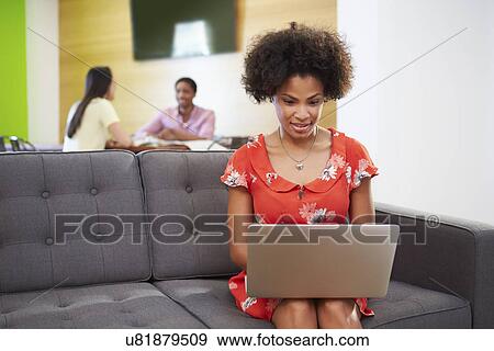 Stock Photo - Woman Taking A Break Working On Sofa In Design Studio . Fotosearch
