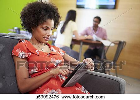 Stock Photograph - Woman Taking A Break Working On Sofa In Design Studio . Fotosearch