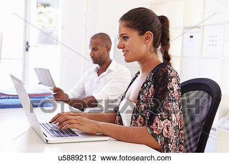 Stock Image - Woman Using Laptop In Modern Office Of Start Up Business. Fotosearch