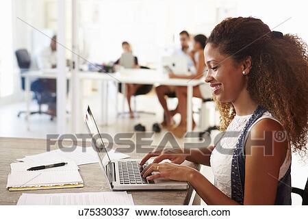 Stock Photo - Woman Using Laptop In Modern Office Of Start Up Business. Fotosearch