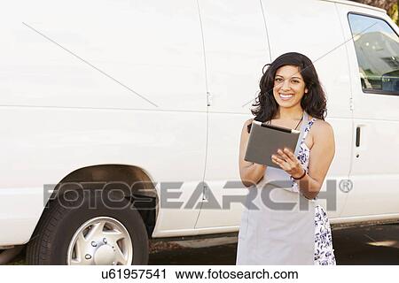 Stock Image - Woman Wearing Apron With Digital Tablet In Front Of Van. Fotosearch