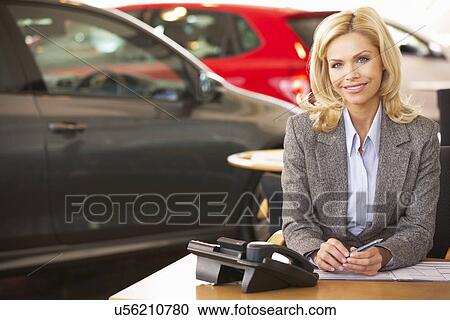 Stock Image - Woman working in car showroom. Fotosearch