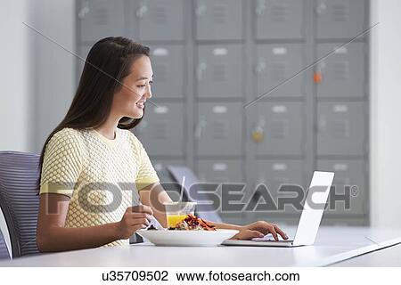 Stock Image - Woman Working In Design Studio Having Lunch At Desk. Fotosearch