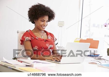 Stock Photograph - Woman Working In Design Studio Having Lunch At Desk. Fotosearch