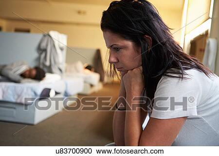 Stock Image - Women Sitting On Beds In Homeless Shelter. Fotosearch