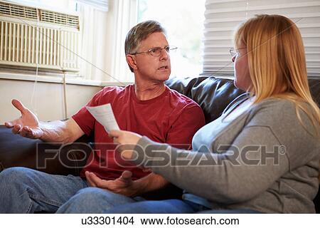 Worried Couple Sitting On Sofa Arguing About Bills View Large Photo Image Picture - Worried Couple Sitting On Sofa Arguing About Bills. Fotosearch