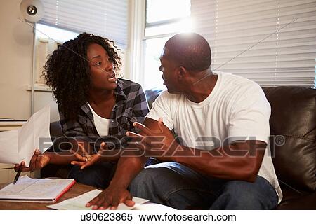 Stock Photography - Worried Couple Sitting On Sofa Arguing About Bills. Fotosearch