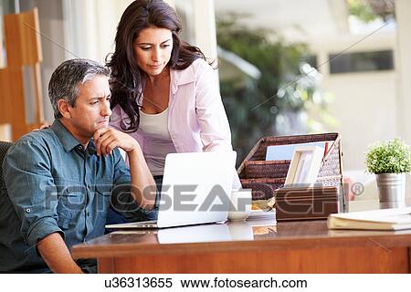 Worried Hispanic Couple Using Laptop On Desk At Home View Large Photo Image Stock Photography - Worried Hispanic Couple Using Laptop On Desk At Home. Fotosearch