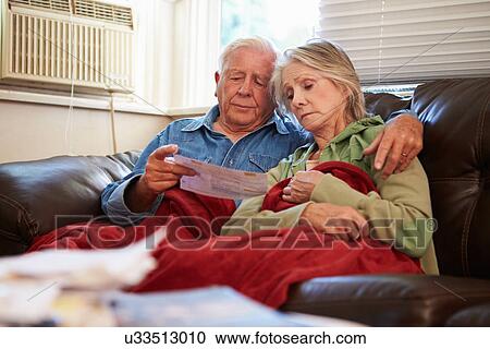 Worried Senior Couple Sitting On Sofa Looking At Bills View Large Photo Image Stock Image - Worried Senior Couple Sitting On Sofa Looking At Bills. Fotosearch