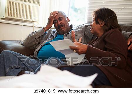 Worried Senior Couple Sitting On Sofa Looking At Bills View Large Photo Image Stock Photo - Worried Senior Couple Sitting On Sofa Looking At Bills. Fotosearch