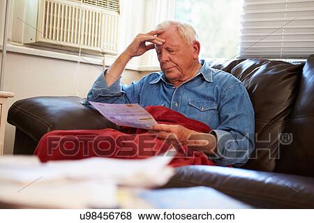 Worried Senior Man Sitting On Sofa Looking At Bills View Large Photo Image Stock Photo - Worried Senior Man Sitting On Sofa Looking At Bills. Fotosearch