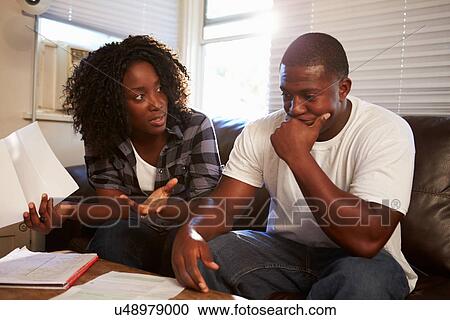 Worried Young Couple Sitting On Sofa Looking At Bills View Large Photo Image Stock Image - Worried Young Couple Sitting On Sofa Looking At Bills. Fotosearch