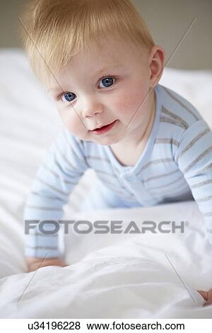 Stock Photo - Young Baby Boy Playing In Bed. Fotosearch