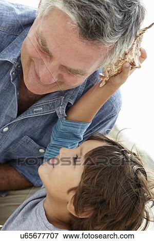 Stock Photo - Young boy and grandfather with seashell. Fotosearch
