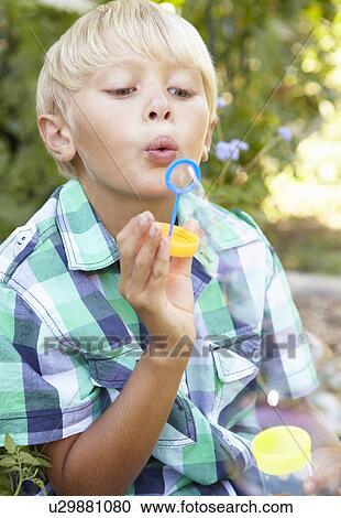 Stock Image - Young boy blowing bubbles. Fotosearch