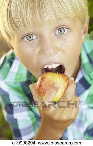 Young boy eating apple View Large Photo Image Picture - Young boy eating apple. Fotosearch