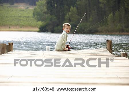 Stock Photo - Young boy fishing on a jetty. Fotosearch