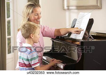 Stock Image - Young boy in lesson with piano teacher. Fotosearch