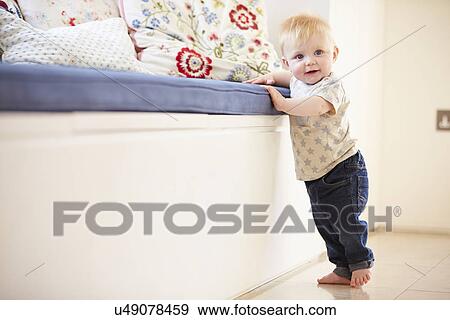 Young Boy Learning To Walk By Holding Onto Furniture View Large Photo Image Stock Photo - Young Boy Learning To Walk By Holding Onto Furniture. Fotosearch