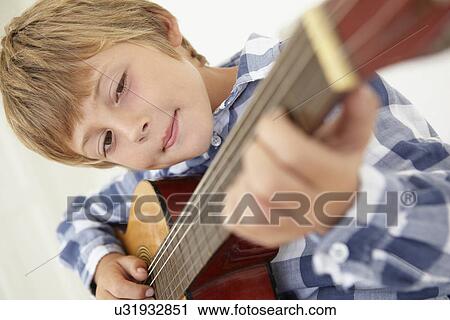 Stock Image - Young boy playing acoustic guitar. Fotosearch