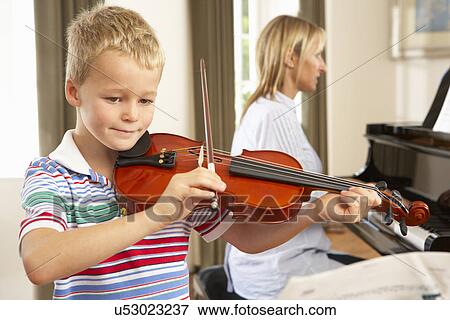 Young boy playing violin accompanied by teacher View Large Photo Image Stock Photo - Young boy playing violin accompanied by teacher. Fotosearch