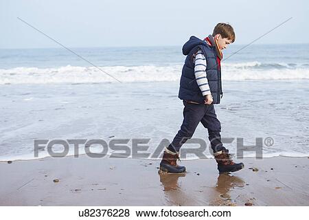 Stock Photo - Young Boy Walking Along Winter Beach. Fotosearch