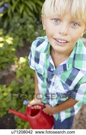 Stock Image - Young boy watering garden. Fotosearch