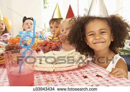 Picture - Young children eating at birthday party. Fotosearch