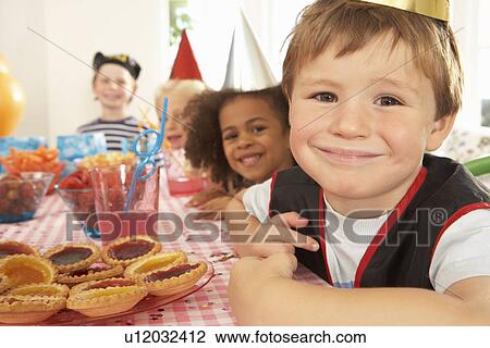 Stock Image - Young children eating at birthday party. Fotosearch