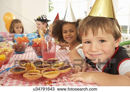 Stock Image - Young children eating at birthday party. Fotosearch