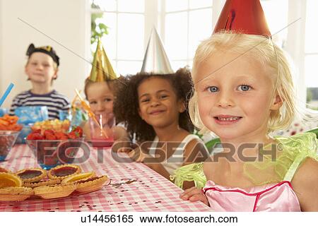 Stock Photography - Young children eating at birthday party. Fotosearch