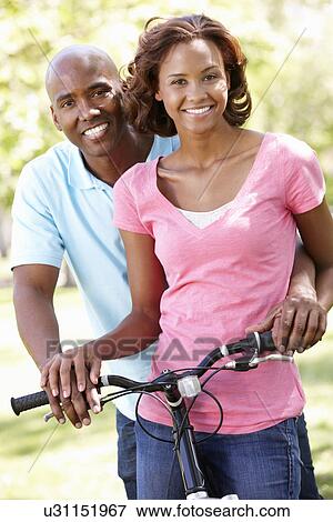 Stock Photo - Young couple cycling in park. Fotosearch