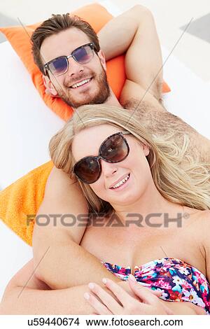 Young Couple On Holiday Relaxing By Swimming Pool View Large Photo Image Picture - Young Couple On Holiday Relaxing By Swimming Pool. Fotosearch