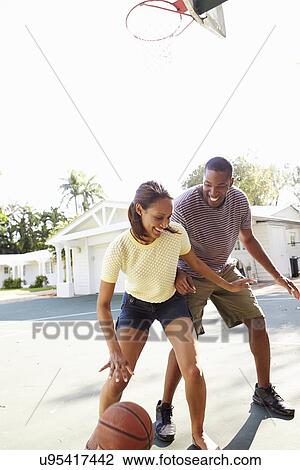 Stock Image - Young Couple Playing Basketball Together. Fotosearch