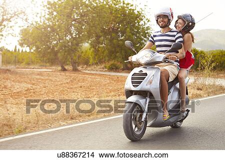 Picture - Young Couple Riding Motor Scooter Along Country Road. Fotosearch