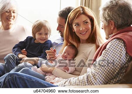 Stock Image - Young Couple Sitting On Roof Terrace Using Laptop. Fotosearch
