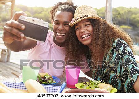 Stock Image - Young Couple Taking Selfie During Lunch Outdoors. Fotosearch
