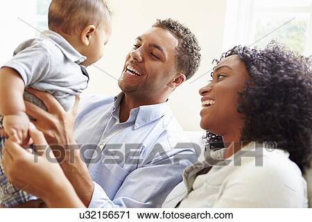 Stock Image - Young Family Playing With Happy Baby Son At Home. Fotosearch