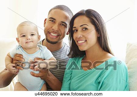 Stock Image - Young Family Playing With Happy Baby Son At Home. Fotosearch