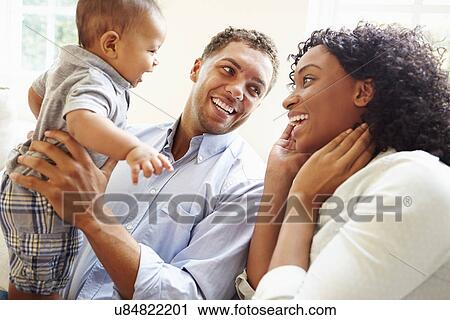 Stock Image - Young Family Playing With Happy Baby Son At Home. Fotosearch