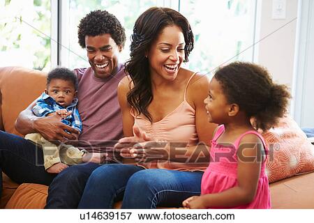 Stock Photo - Young Family Relaxing On Sofa Together. Fotosearch