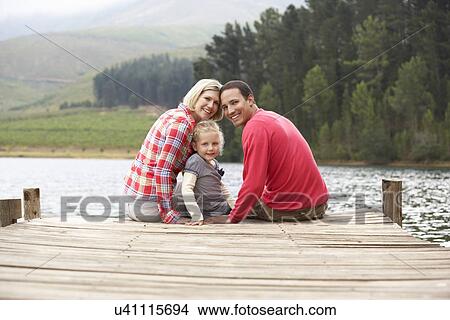 Picture - Young family sitting on a jetty. Fotosearch