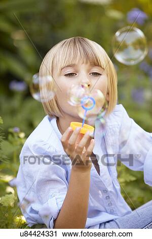Stock Image - Young girl blowing bubbles. Fotosearch