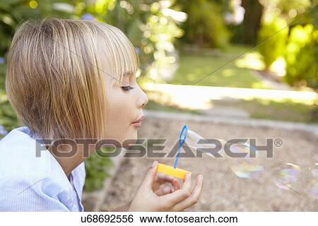 Stock Photograph - Young girl blowing bubbles. Fotosearch