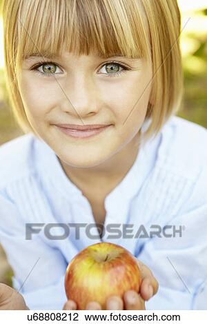 Stock Image - Young girl holding apple. Fotosearch