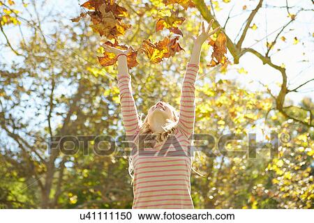 Stock Image - Young Girl Throwing Autumn Leaves In The Air. Fotosearch
