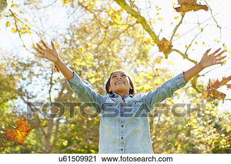 Stock Image - Young Girl Throwing Autumn Leaves In The Air. Fotosearch