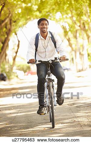 Stock Image - Young Man Cycling Along Street To Work. Fotosearch
