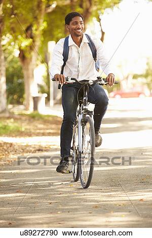 Stock Image - Young Man Cycling Along Street To Work. Fotosearch